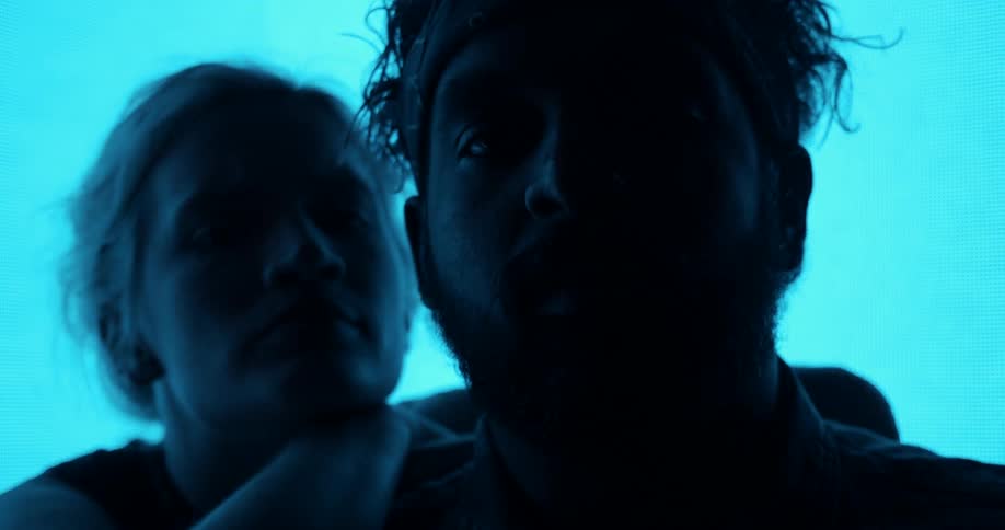 A man and a woman in a room with a big screen in the background