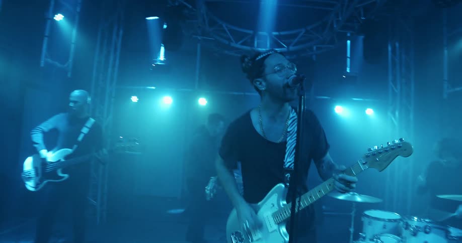 A band playing on a stage with blue lighting