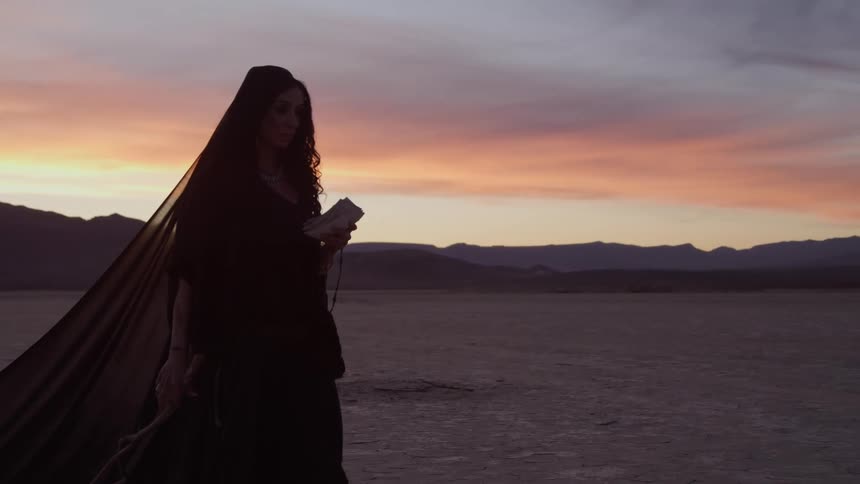 A woman is wearing a dress and walking outdoors at dusk
