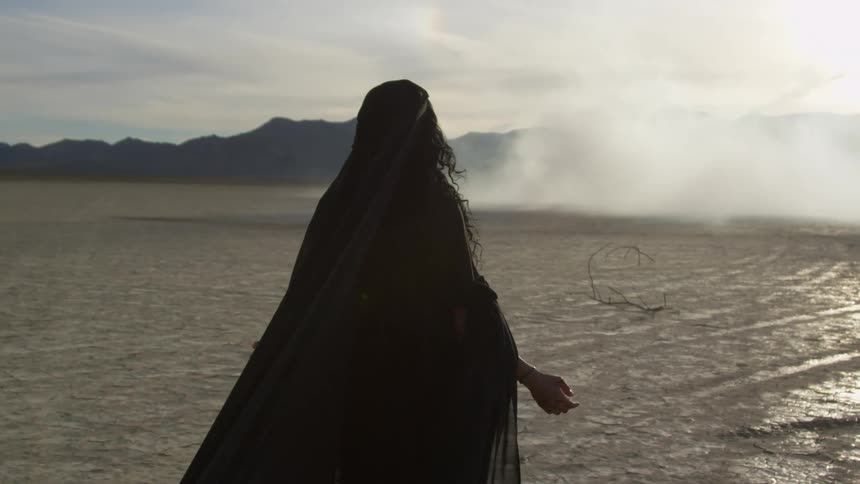 A woman walking on dirt wearing a dress