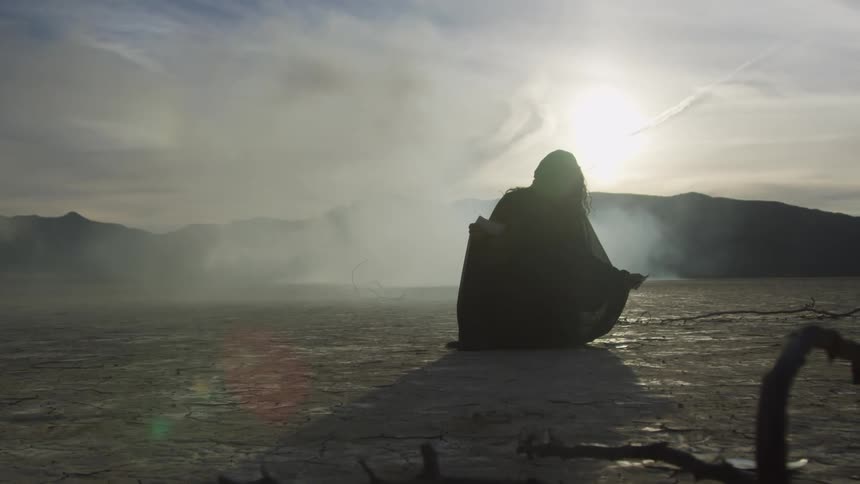 A person bending over and picking up something on a lake bed