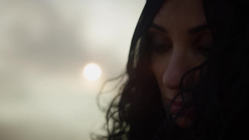 A woman is standing outdoors at dusk
