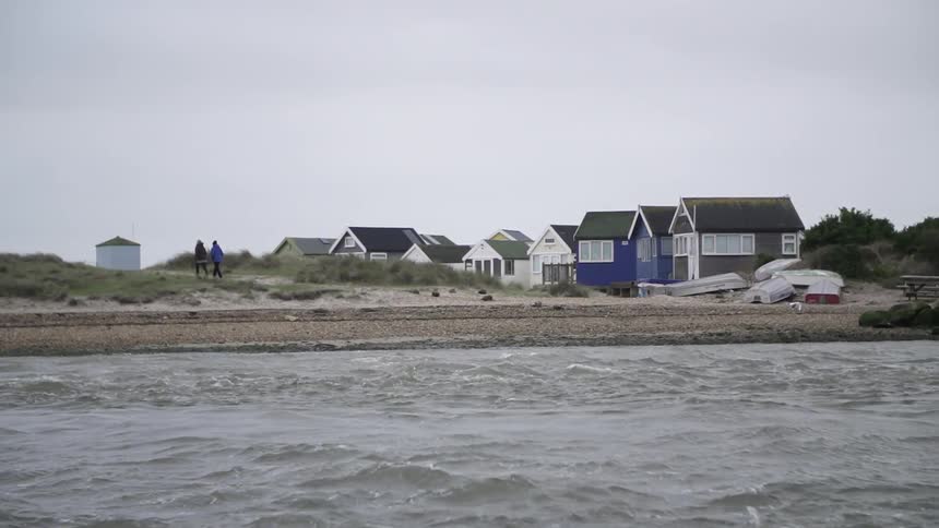 Two people walking away from a beach on a cold day