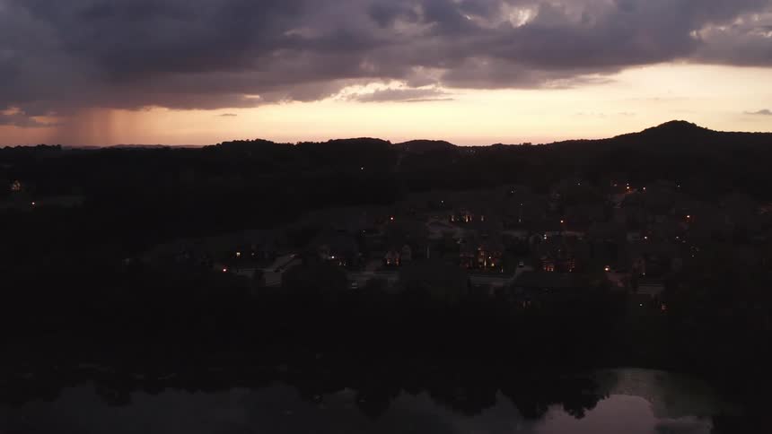 Neighborhood with a nearby lake in a forested mountain area under a cloudy sky