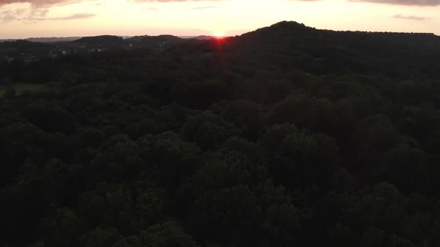 Sun rising over forested mountains