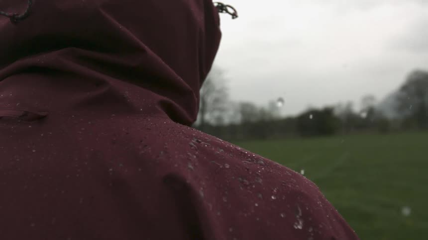Raindrops fall on the hooded jacket of a person