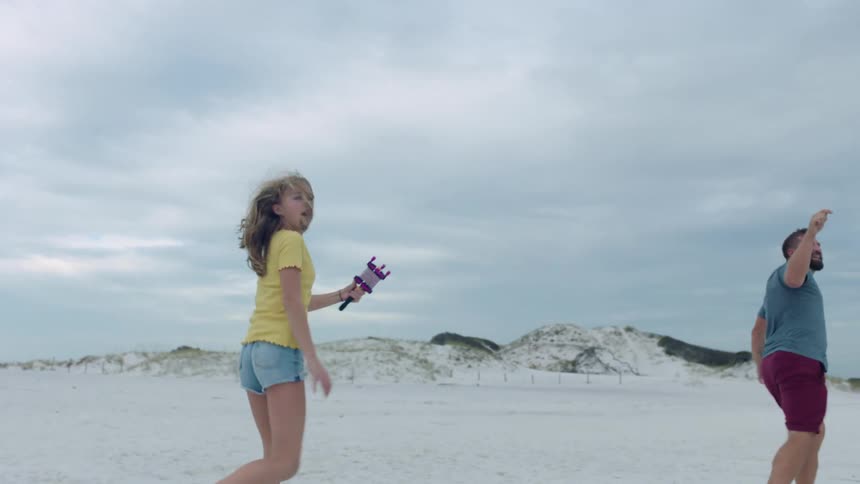 A man and girl fly a kite on the beach