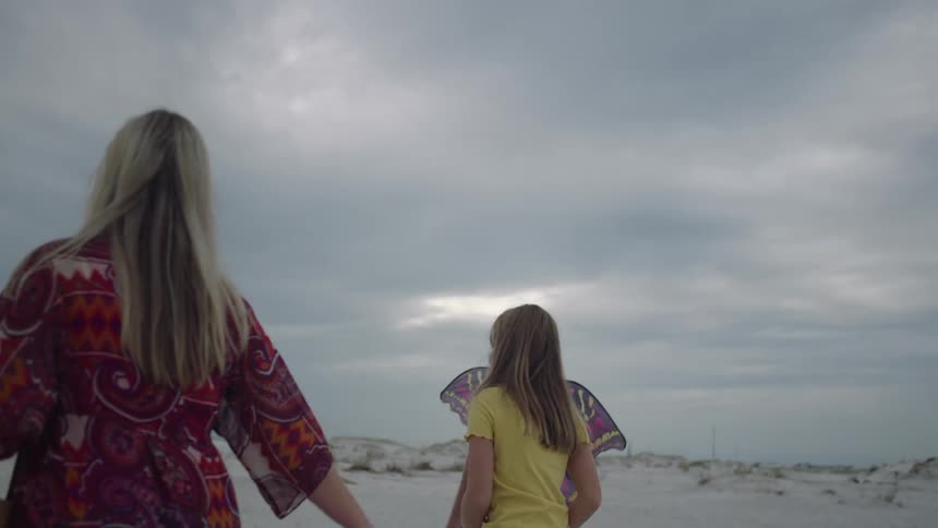 Father mother and daughter walk along the beach on a cloudy day