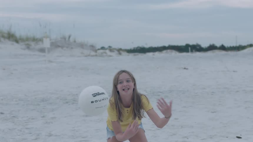 Mother and teenage daughter playing with a volleyball on the sand of a beach