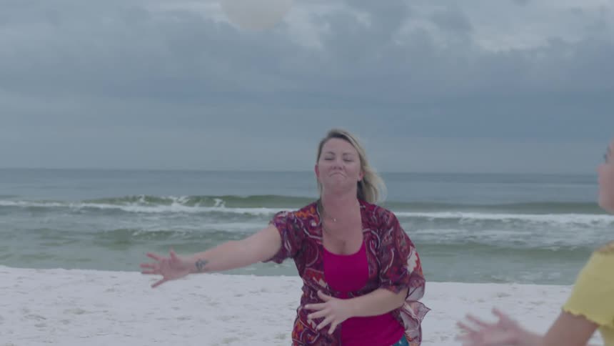 A family playing volleyball on the beach as waves crash on shoreline