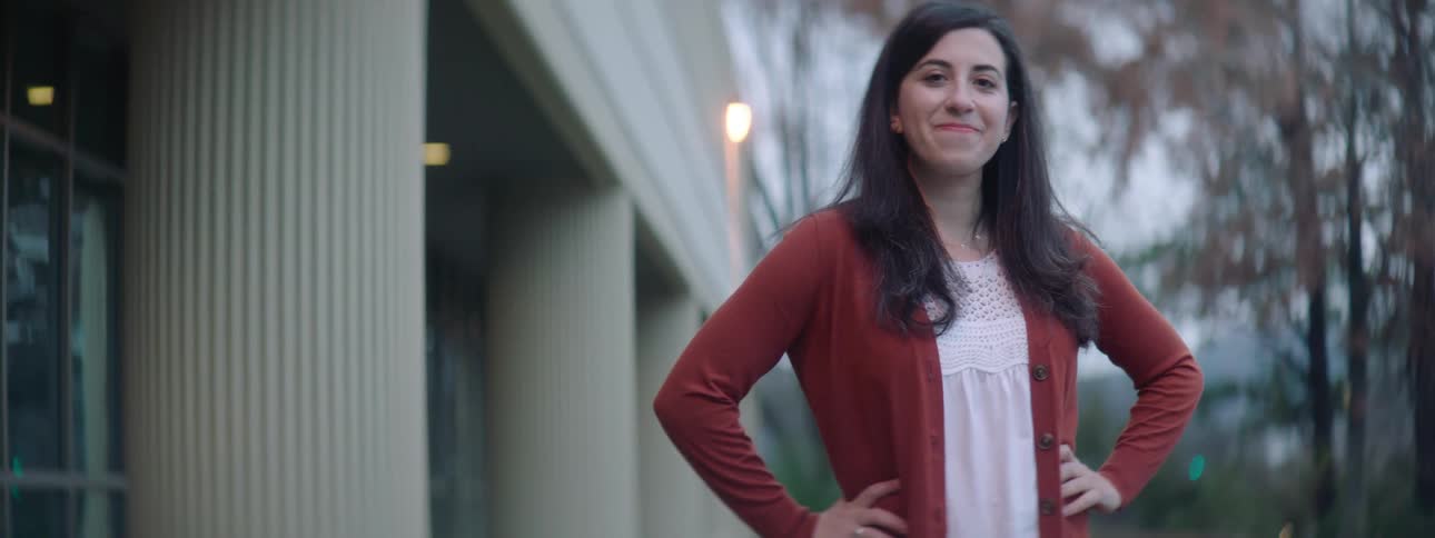 Young woman standing outside a building turns around to look at the camera