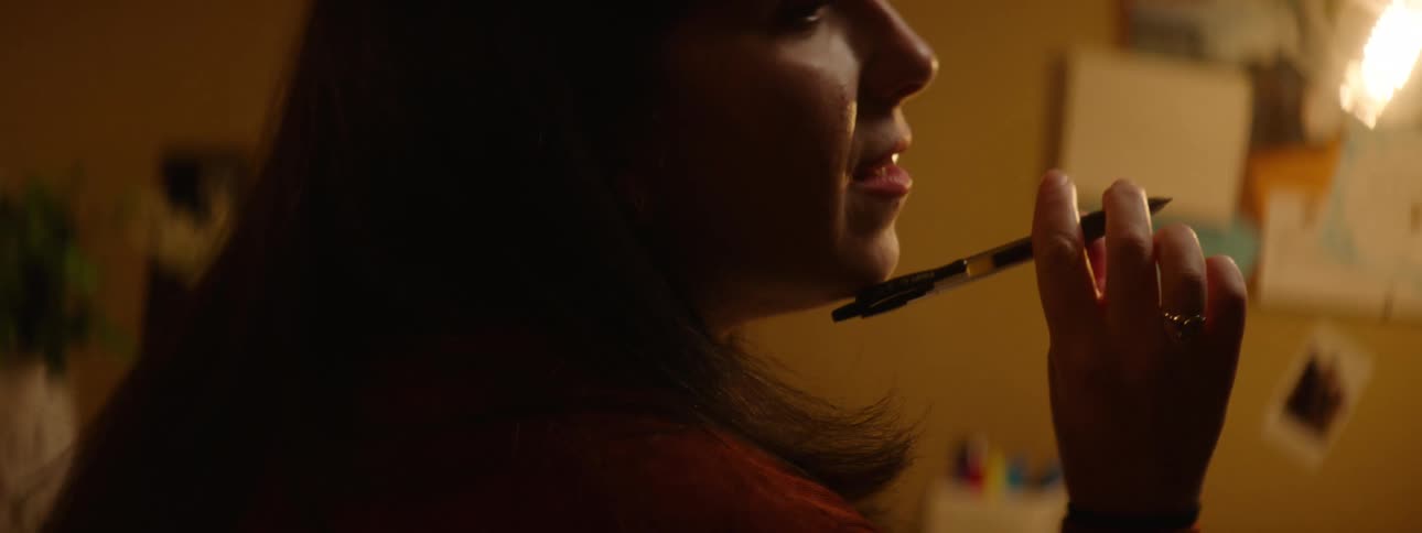 A woman sitting at a desk writing on a book with a pen