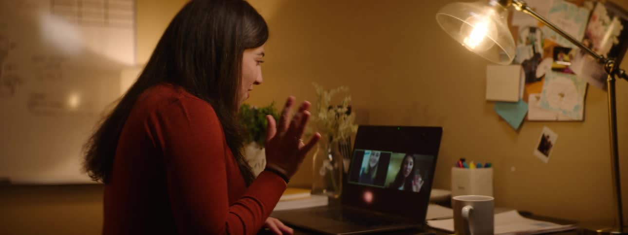 Woman saying goodbie to friends on a video call through a laptop at home
