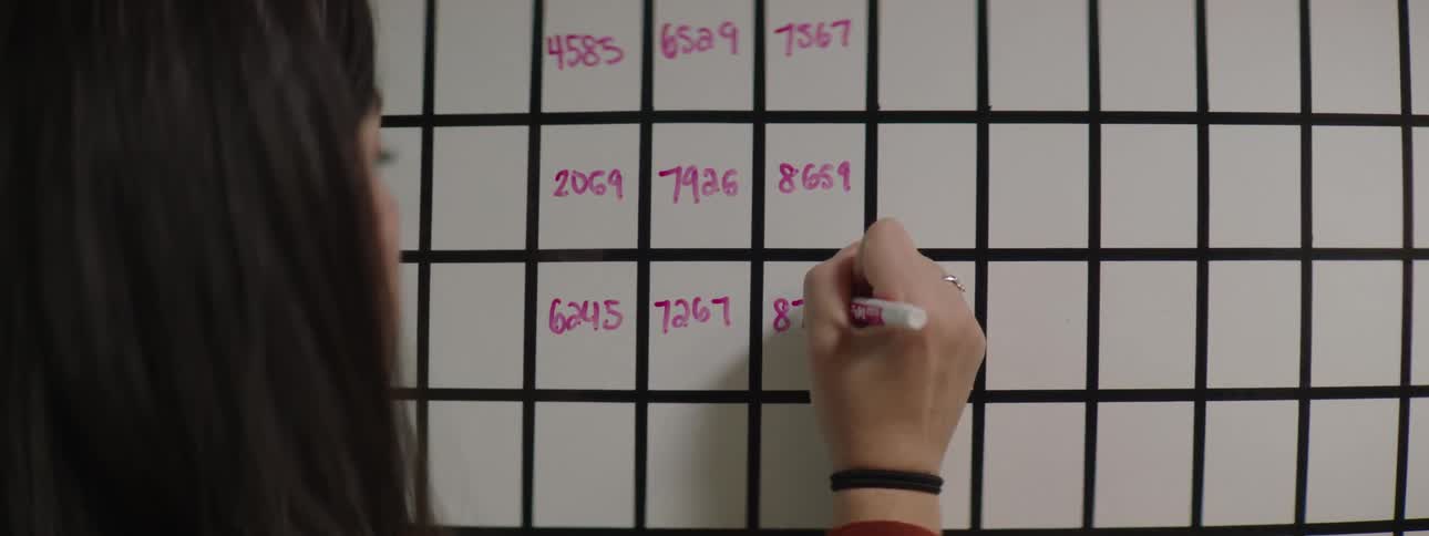 Woman writing on a whiteboard on the office wall with a pink pen