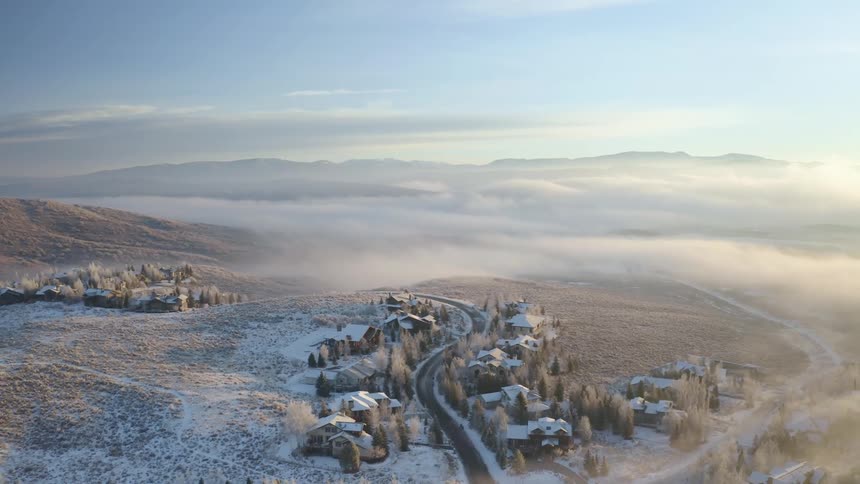 Aerial view of a snow covered small town in the plains near the mountains at sunset