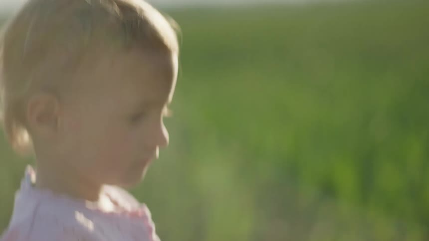 A child is walking on a field of grass at dusk