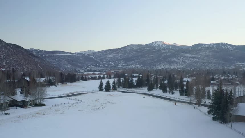 An aerial view of a small town surrounded by snowy mountains in winter