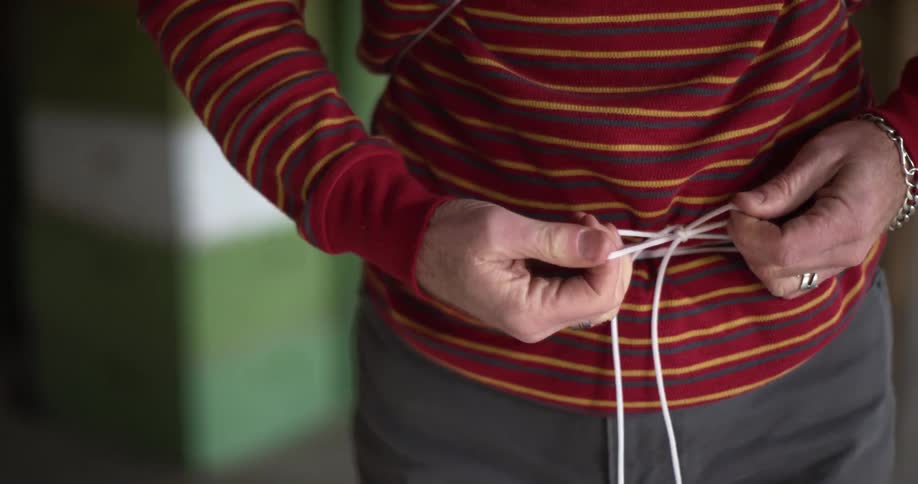 A man ties a white string around his waist