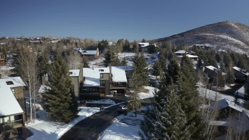 A town with houses roads with vehicles and trees covered in snow