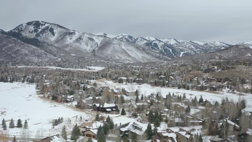 A small town is covered in snow with mountains in the background