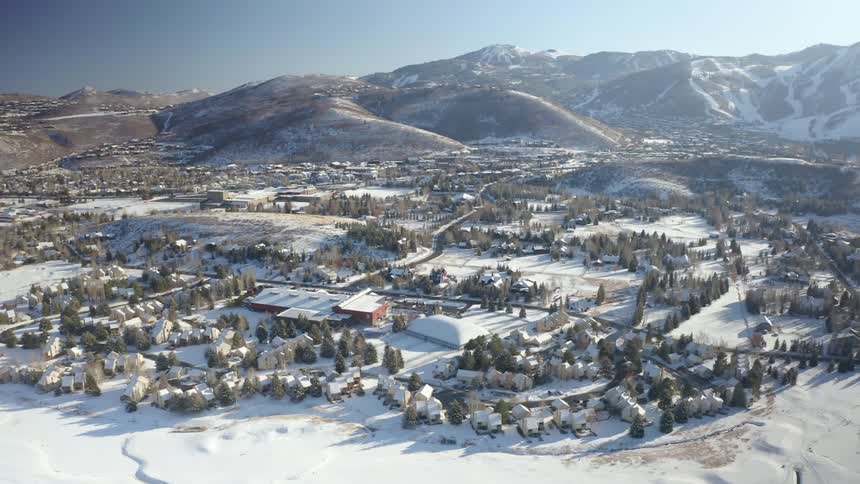Aerial view of a small neighborhood next to a large mountain range during the winter at daytime