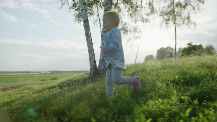 Father catches little daugther running on the green grass on a field at morning