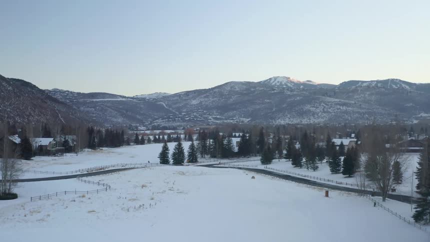 Snow covered rural community with many trees and mountains on the horizon