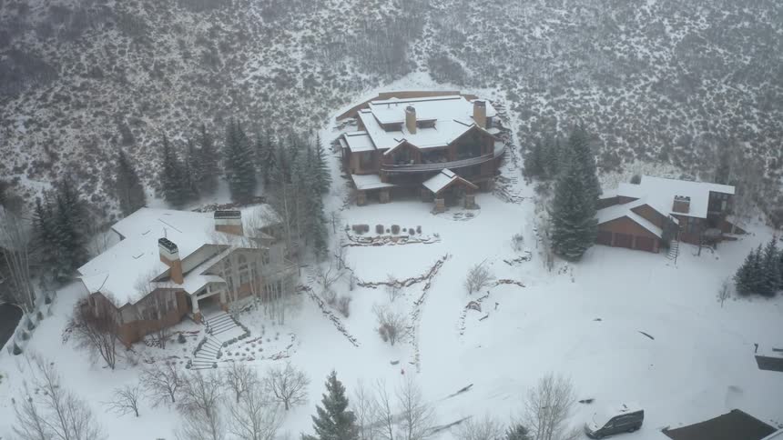 A town with houses a vehicle and trees covered in snow