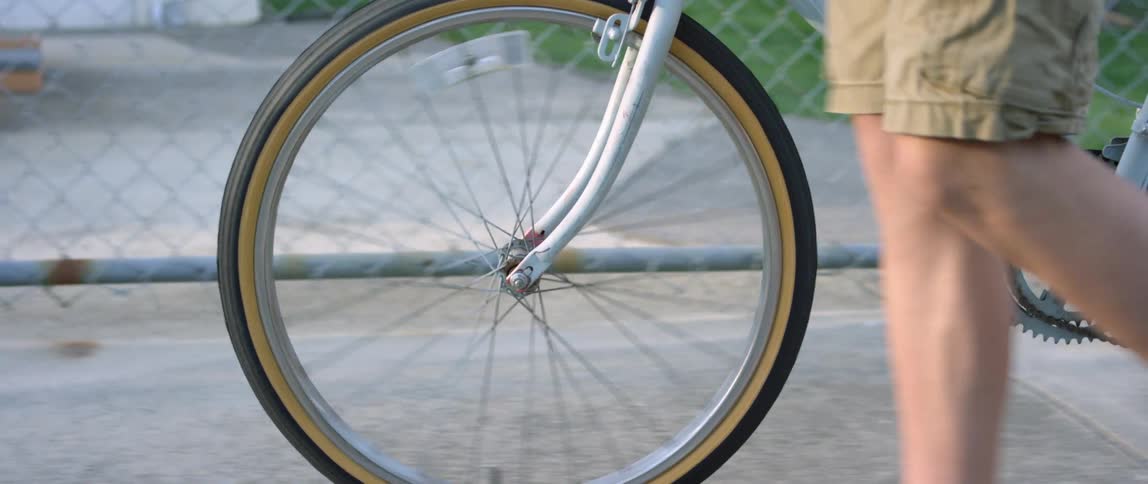 A man that is walking down a sidewalk with a bicycle