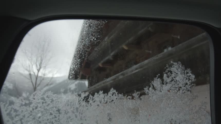 Frost covers the bottom half of a vehicles window on a snowy winter day