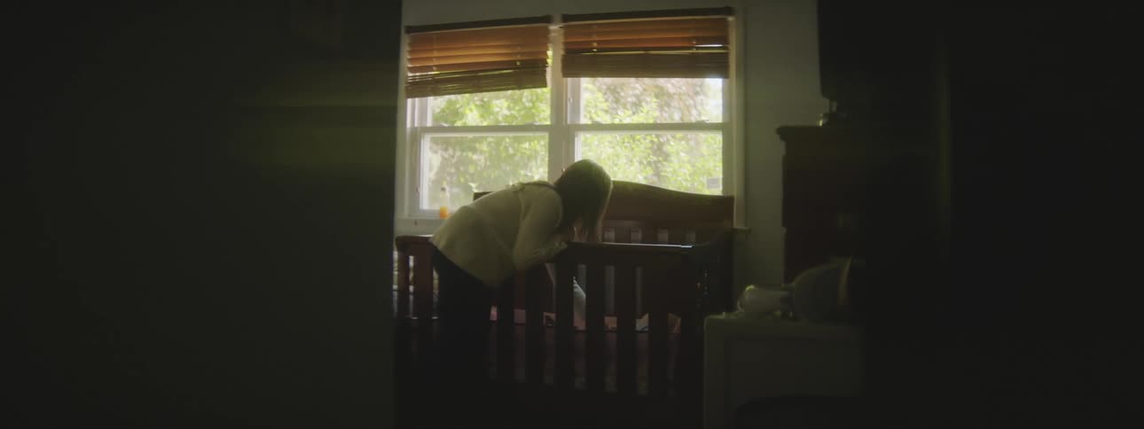 Mother caressing her baby in the crib at home