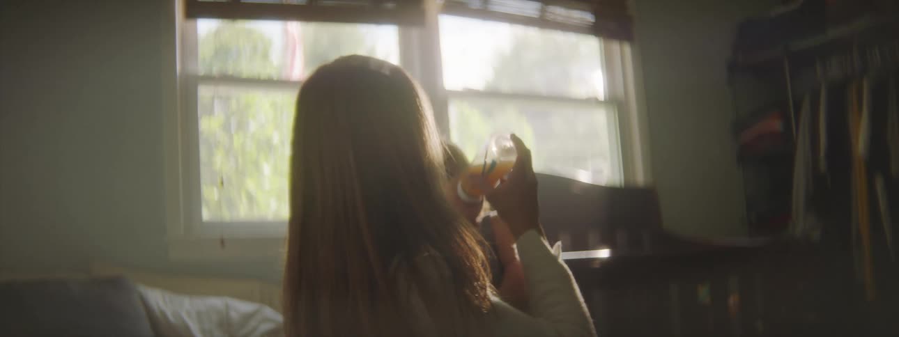A mother rocks her child while feeding them with a bottle in a bedroom during the day