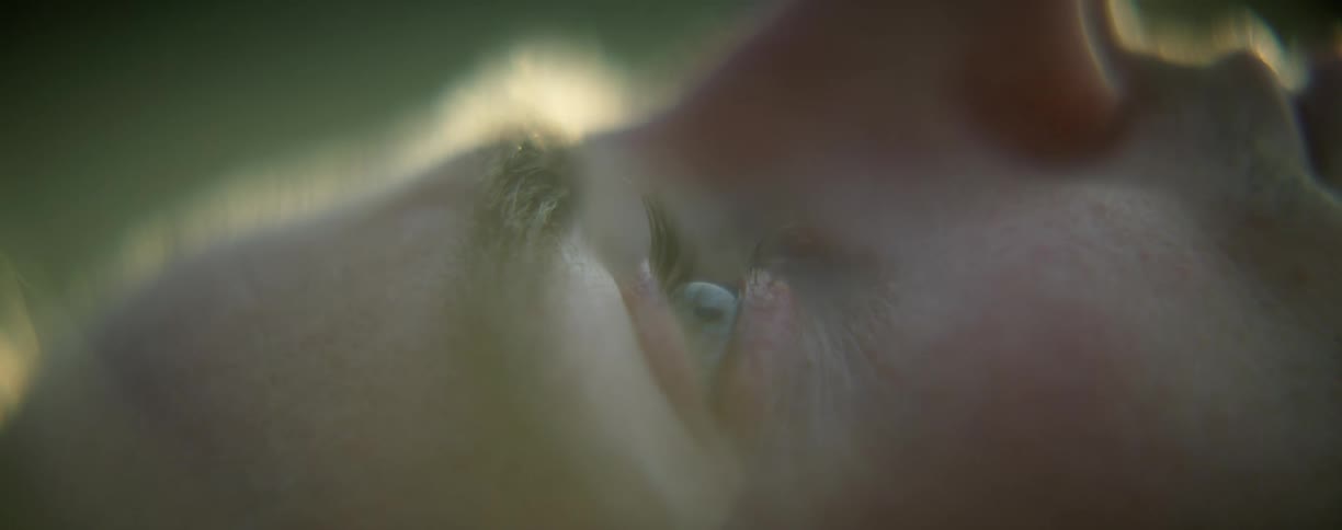 A man laying on grass looking upwards and thinking