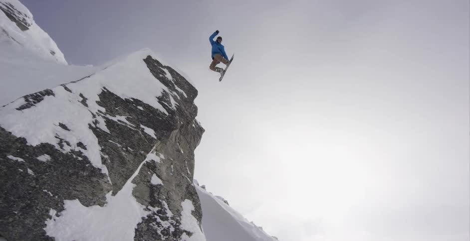 A snowboarder jumping off a cliff
