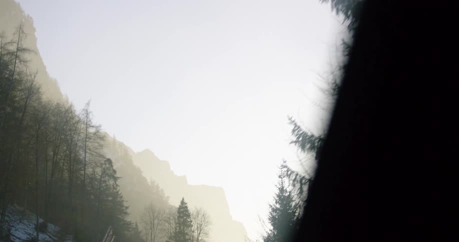 A vehicle driving with a windshield with a mountain range the sky and clouds in the background