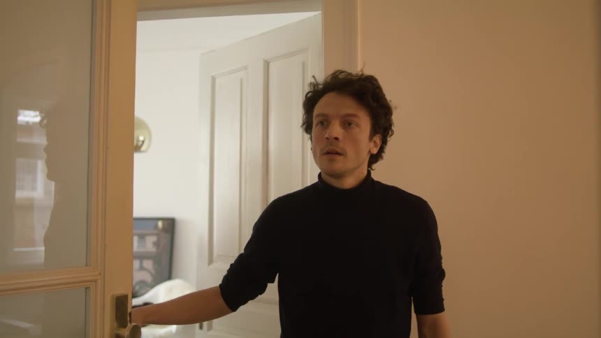A man opens the door at home welcoming a woman to come inside