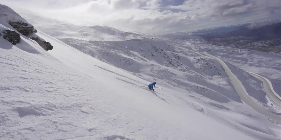 A person on a snowboard does a jump off the top of a hill