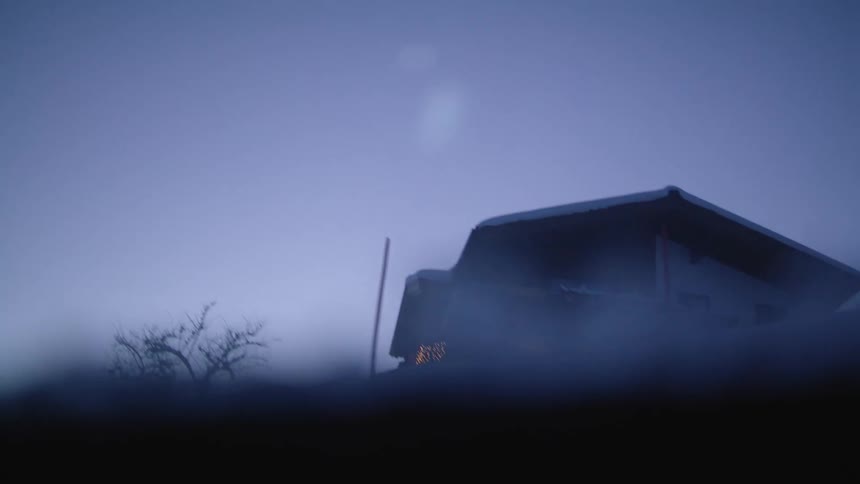 A vehicle with windows with a house trees the sky and clouds in the background