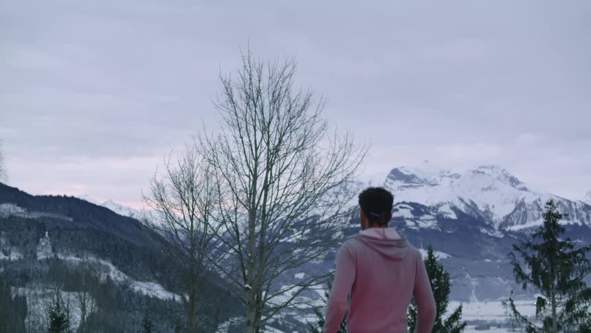 A man runs in place above a lake in front of the mountains