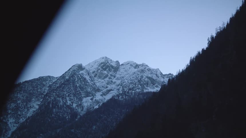 A vehicle with a window and rearview mirror with a mountain range the sky and clouds in the background