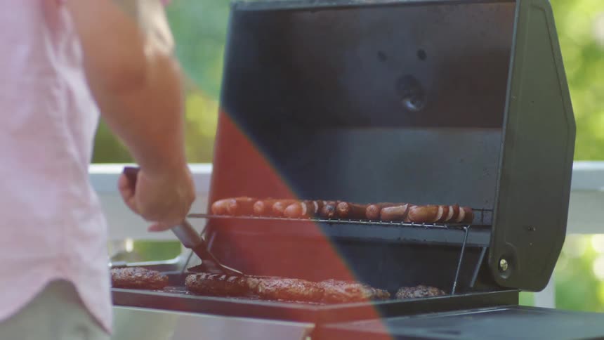 A man is grilling food while standing outdoors