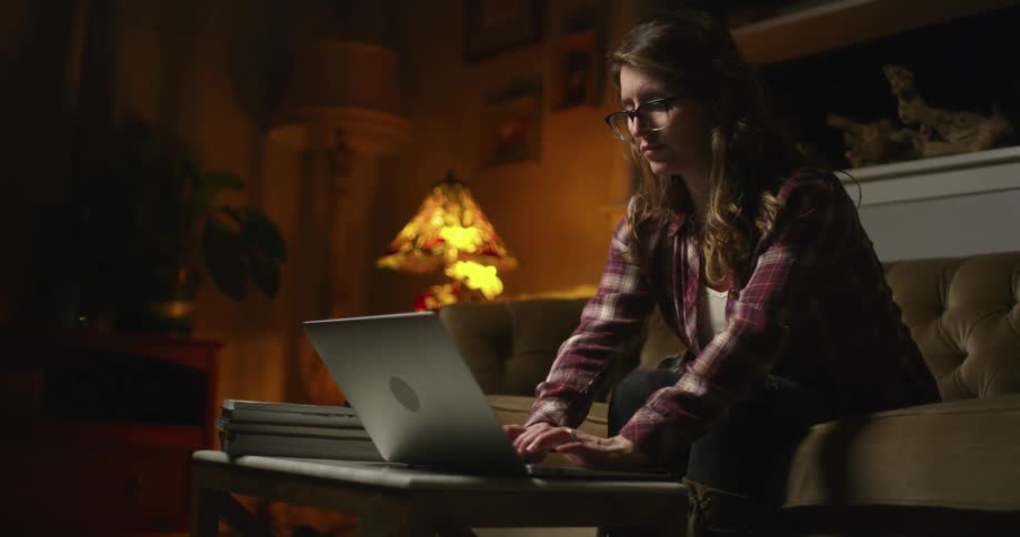 A woman typing on the keyboard of a laptop over a coffee table in the living room