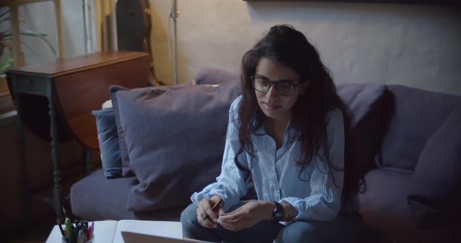 A woman writing in a book next to a laptop