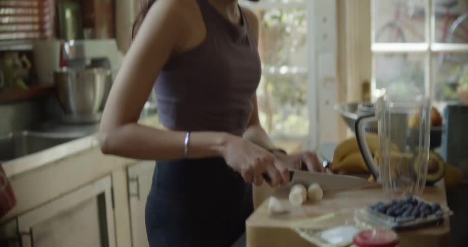 A woman cutting up a banana in a kitchen