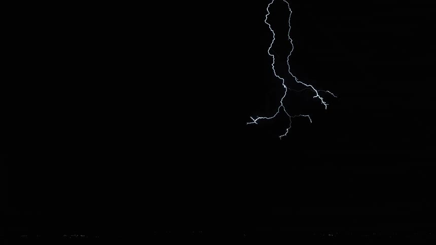 Lightning bolts flash and branch out in a dark sky before hitting the ground