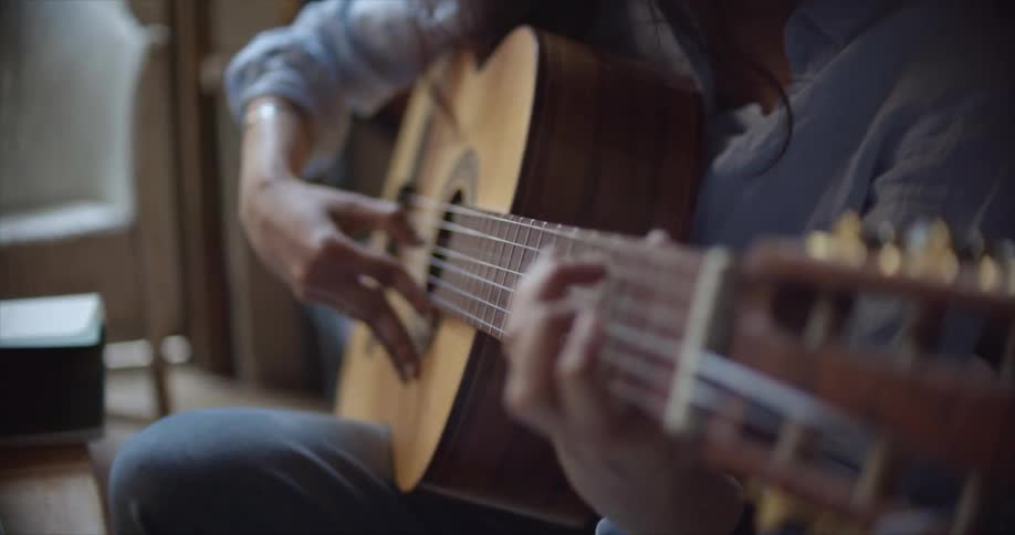 A woman is playing the guitar at home