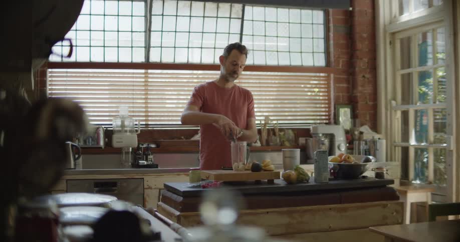 A man is making a smoothie with fruit