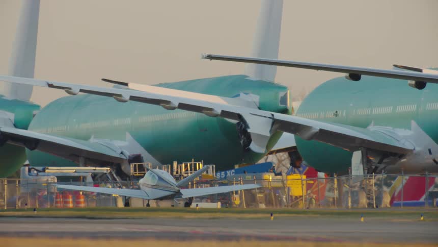 Tight shot of a Beechcraft v tail Bonanza taxiing next to massive under construction Boeing Commercial jets at Paine Field IATA: PAE, ICAO: KPAE, FAA LID: PAE, also known as Snohomish County Airport