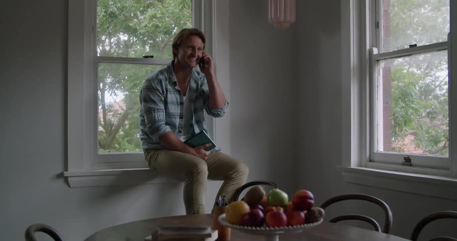 Man happily answers a call on his smartphone at home