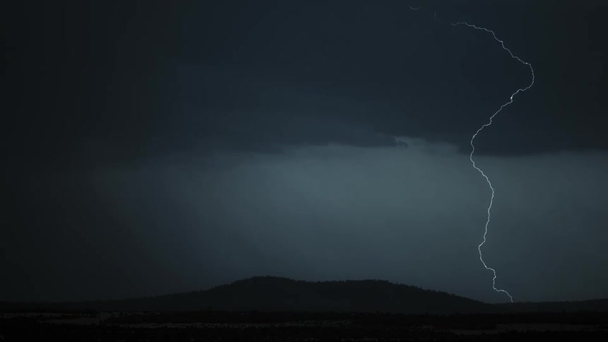 Bolts of lightning strike the ground beneath ominous and gray storm clouds